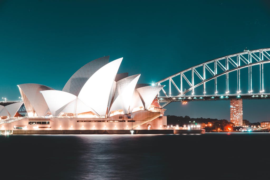 Stunning night view of Sydney Opera House and Harbour Bridge, beautifully illuminated against a clear sky.